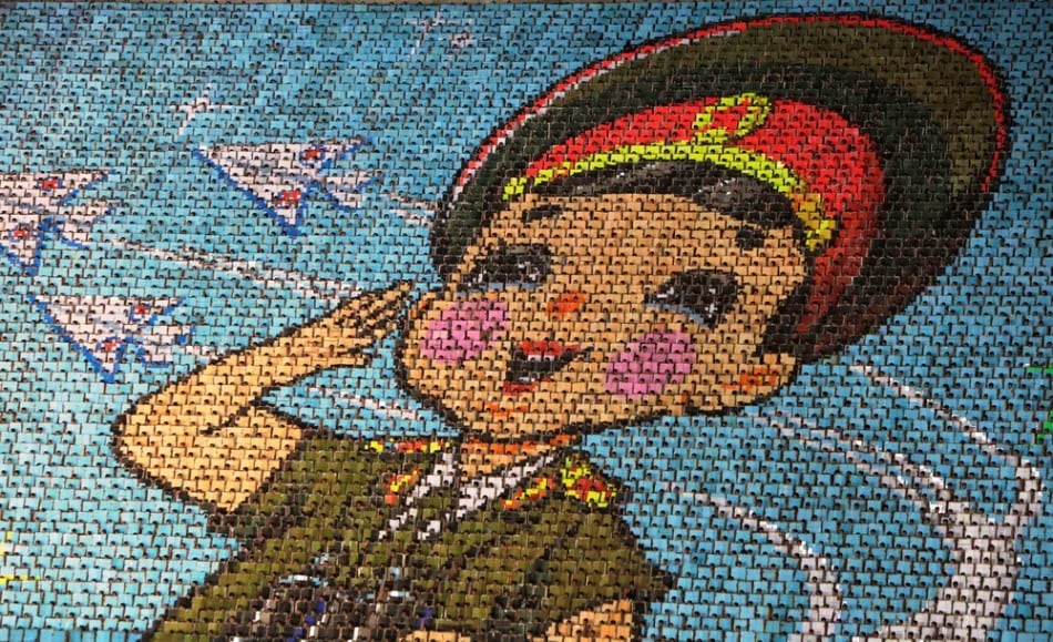 North Korean students use different colored cardboard to form a picture of a child in uniform as a background during a mass gymnastic and artistic performance “Arirang”, in Pyongyang July 26, 2013. The games are the world's biggest choreographed extravaganza, part circus act, part rhythmic gymnastics floor, with plenty of reverence for the late North Korean leader Kim Jong-il. (Photo by Jason Lee/Reuters)