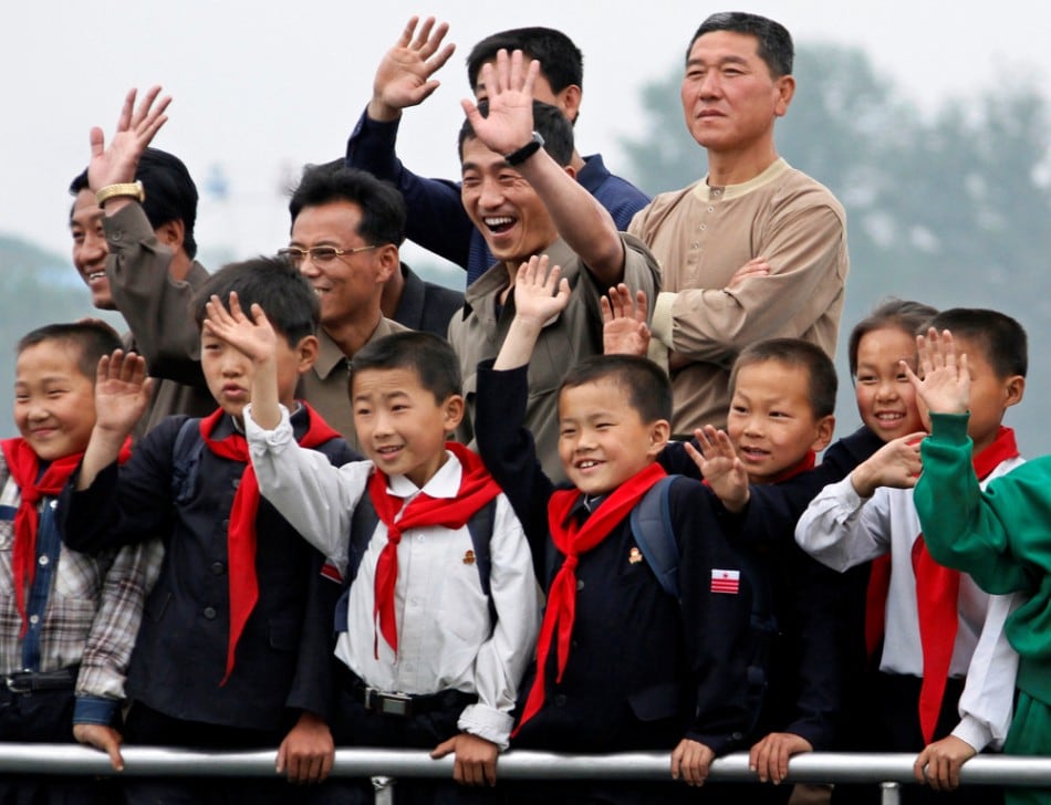 North Korean children and their parents wave to Chinese residents as they take a tour on a boat to celebrate International Children's Day on the Yalu River near the North Korean town of Sinuiju, opposite the Chinese border city of Dandong, June 1, 2011. (Photo by Jacky Chen/Reuters)