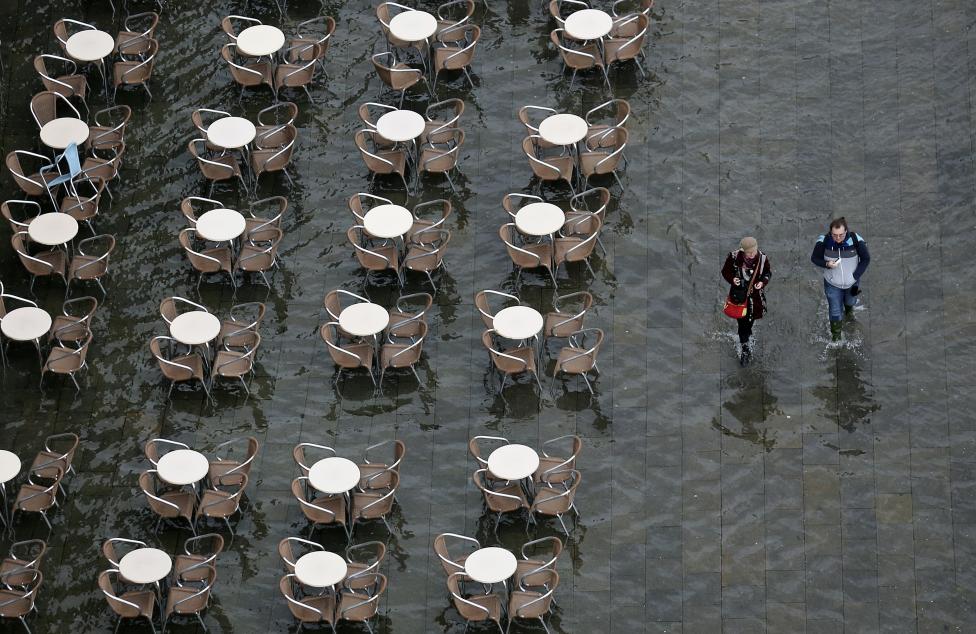 people walk on the flooded st. mark's square during a period of seasonal high water and on the first day of carnival, in venice