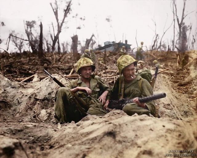 Marine Pfc. Douglas Lightheart (right) cradles his .30 caliber M1919 Browning machine gun in his lap, while he and Marine Pfc. Gerald Thursby Sr. take a cigarette break, during mopping up operations on Peleliu on 14th September 1944. (Colorized by Paul Reynolds. Historic Military Photo Colourisations)