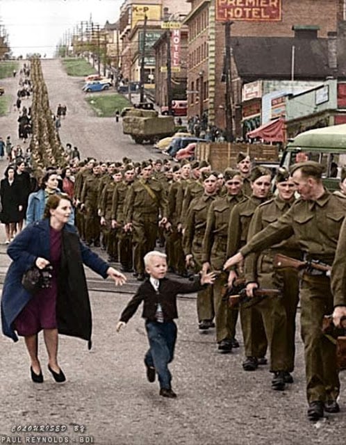On October 1, 1940, Private Jack Bernard and other volunteers in The British Columbia Regiment (Duke of Connaught’s Own Rifles) were marching smartly down Eighth Street in New Westminster to board a ship and sail off to war. Suddenly, Bernard’s five-year-old son broke free of his mother’s grasp and sprinted into the military formation to take his smiling father’s hand. In that instant, an alert Vancouver Daily Province photographer, Claude Dettloff, snapped the shutter. Soon, his unforgettable image of little Warren “Whitey” Bernard was being printed by leading publications throughout North America. It was later used in Canada’s war bond drives with the plea, “help bring my Daddy home.” Jack Bernard survived the war and was reunited with his son in 1945. (Claude Dettloff, photographer - City of Vancouver Archives online database. Colorized by Paul Reynolds. Historic Military Photo Colourisations)