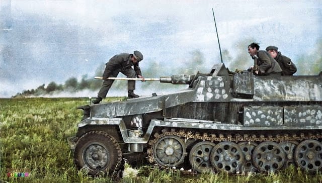 A crew member cleaning the barrel of an Sd.Kfz. 251/9 - Schützenpanzerwagen (7.5 cm KwK 37 L/24) "Stummel" on the East Front, c. Summer 1942. (Colorized by Royston Leonard from the UK)