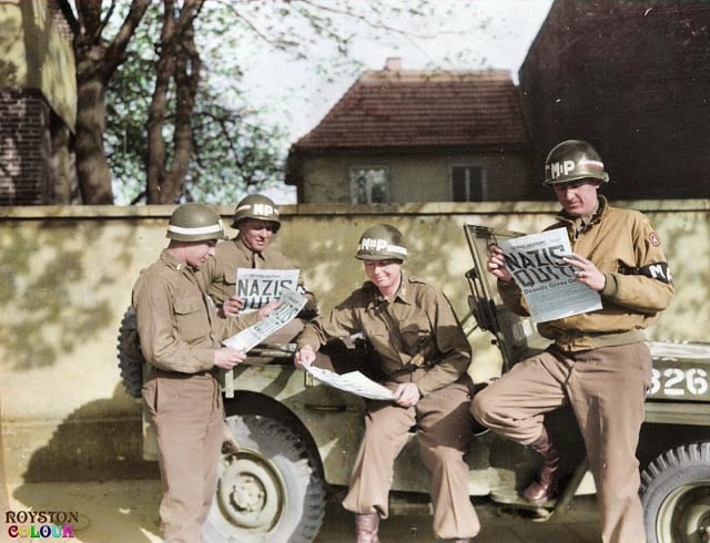 9th Army MPs reading of the surrender in the 'Stars and Stripes' in Germany on the 8th of May 1945. (Source - U. S. Army Military History Institute - Nelson A. Shuey Photograph Collection. Colorized by Royston Leonard UK)