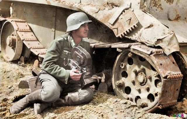 A Kriegsberichter (war correspondent) holding an Arriflex 35 2 1942 camera 35mm ACR 0292 and he is leaning against a knocked out Soviet BT-5 light tank. c.1940/41. (Colorized by Royston Leonard from the UK)