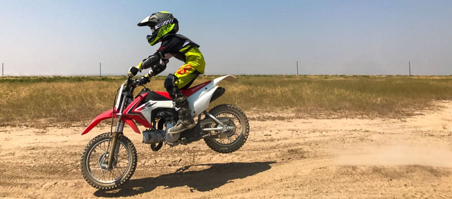 A person flying through the air while riding a motorcycle down a dirt road
Description automatically generated