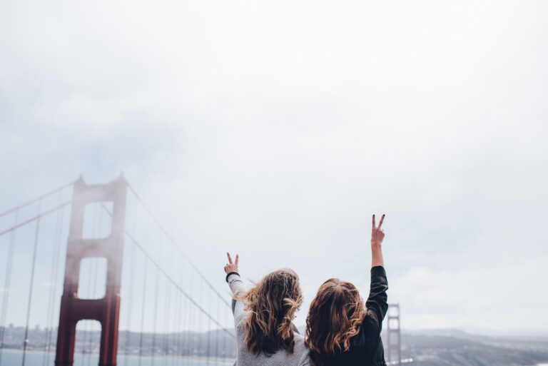 two women making peace sign near the golden gate bridge