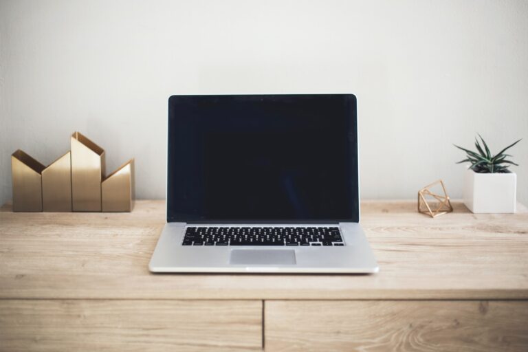 an open laptop computer sitting on top of a wooden table